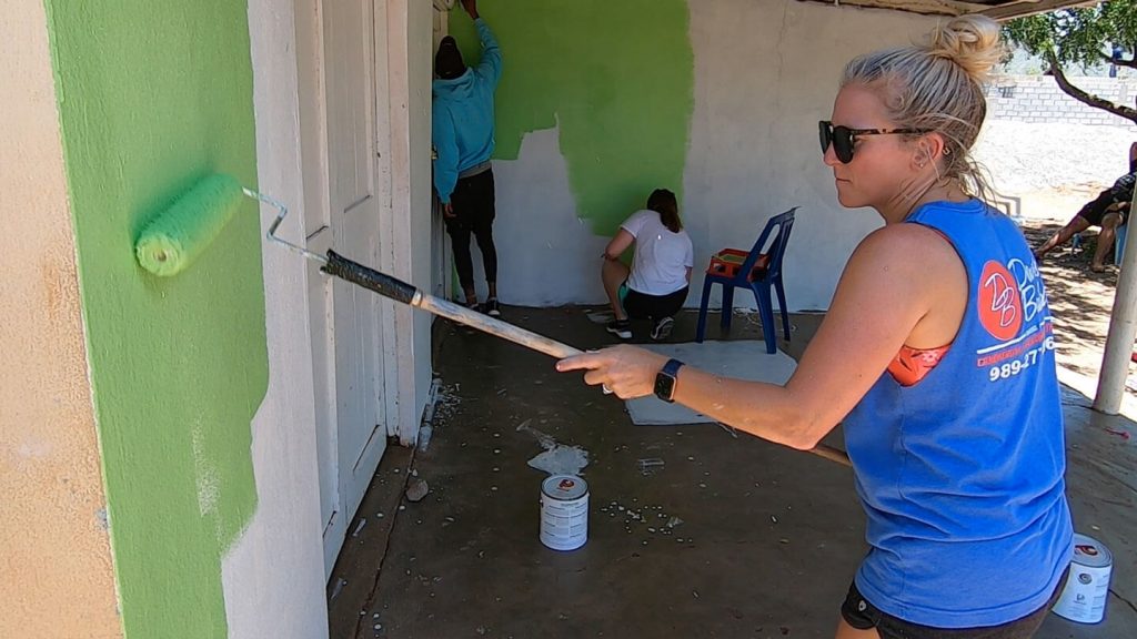 A volunteer painting the side of a house